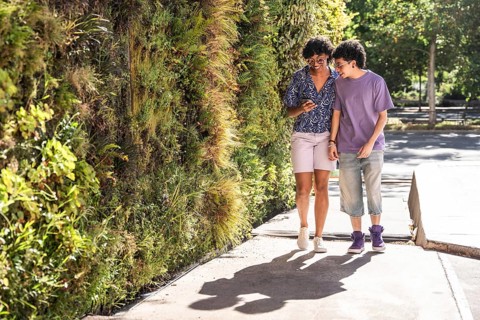 A loving multiethnic LGBTQ+ couple smiles as they enjoy a sunny day, walking side by side along a
