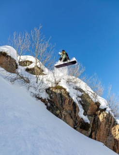 A daring snowboarder leaps off a snowy cliff, showcasing thrilling winter sports skills against a