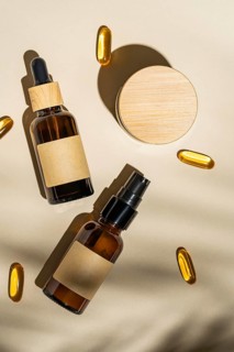 Top view of an amber glass cosmetic bottles with blank labels surrounded by soft shadows and golden