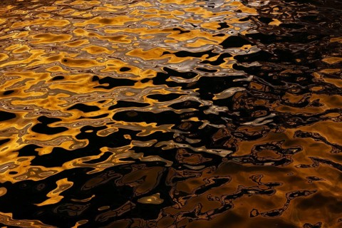 Artistic close-up of shimmering water reflecting golden hues under sunlight at Playa Blanca Port,