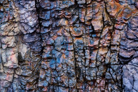 Intricate textures and vibrant mineral hues of the volcanic rock formations in Mujeres Beach,