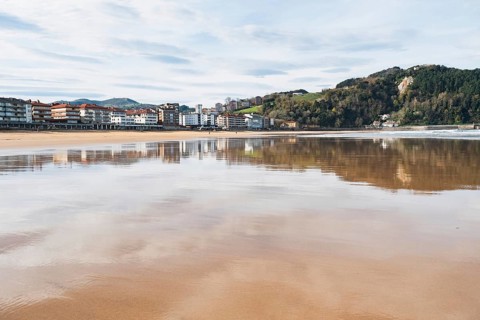 A serene image capturing a coastal town's reflection on a calm bay under a clear sky, showcasing