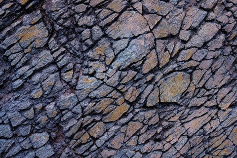 Detailed view of a jagged rock surface with interlocked gray and rust-colored stones in Mujeres