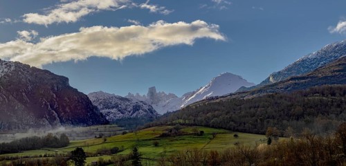 Stunning panoramic view of the mountains, showing snow-capped peaks and lush green valleys under a