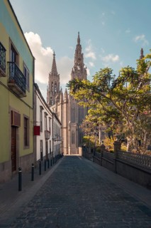 A picturesque view of a cobblestone street in Arucas, leading directly towards the towering spires