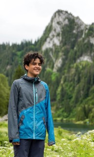 A smiling individual stands against the picturesque backdrop of Lac de Taney, Switzerland,