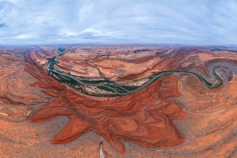 A breathtaking aerial view of a desert landscape. A winding river cuts through red rock San Juan