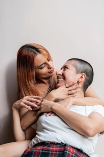 A lesbian couple enjoys a tender embrace, sharing smiles and happiness. Their affectionate
