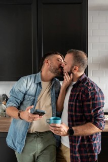 A loving gay couple shares a tender kiss in their kitchen, creating a warm and intimate atmosphere.