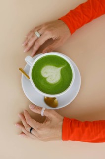 A woman enjoys a matcha latte in a Warsaw cafe Her vibrant orange clothing and trendy rings add