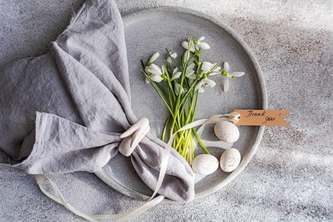 Top view of an exquisite spring table setting featuring fresh snowdrops arranged on a gray ceramic