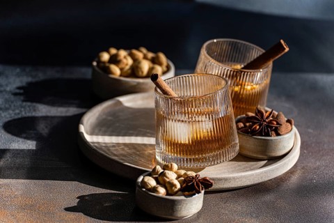 Spiced cognac-based cocktails garnished with cinnamon sticks and star anise, accompanied by