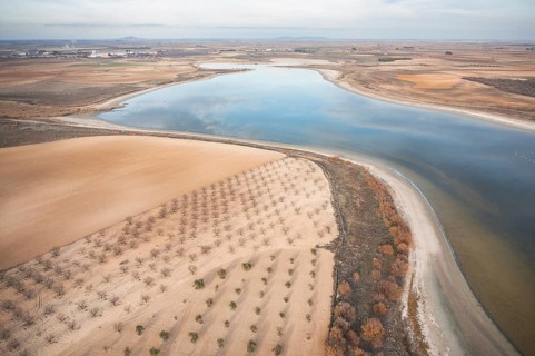 An aerial perspective showcasing a serene lagoon surrounded by cultivated farmland in Toledo, Spain
