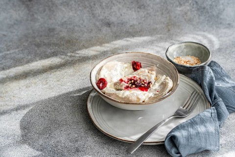 Traditional Ukrainian varenyky filled with cherries, served with rich sour cream and sprinkled with