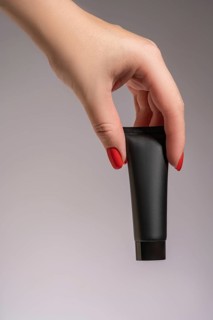 Cropped unrecognizable close-up of a female hand with red manicure elegantly holding a sleek black