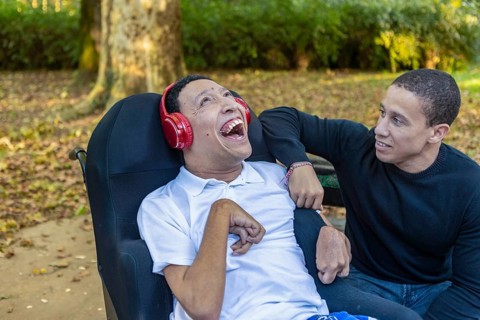 Spanish Cameroonian siblings share a joyful outdoor moment at a park. One sibling, wearing