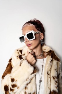 Fashion-forward woman wearing a faux fur coat and oversized white sunglasses, showcasing trendy