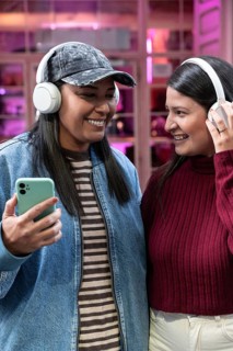 A joyful Latin couple shares a moment, smiling and listening to music with headphones. Their casual
