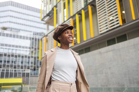 A fashionable black woman walks through an urban area, surrounded by contemporary architecture Her