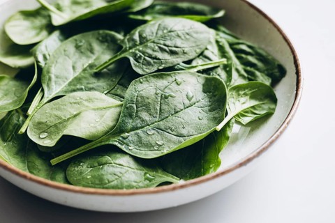 A close-up of fresh green spinach leaves in a bowl, showcasing their vibrant color and freshness