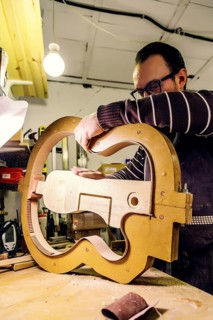 A skilled luthier at work in a workshop, carefully crafting a bass guitar using specialized tools