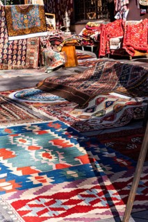 A vibrant collection of traditional Georgian rugs and textiles displayed in an outdoor market in