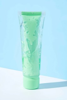 Transparent green tube filled with aloe vera infused cosmetic gel showcased against a light blue