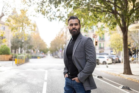 Stylish Indian businessman with a well-trimmed beard stands confidently on an urban street lined