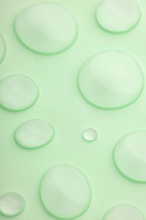 This image features a close-up view of translucent droplets scattered on a smooth, light green