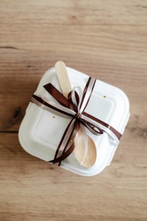 Top view of an elegantly packaged bento birthday cake, tied with a brown satin ribbon and wooden