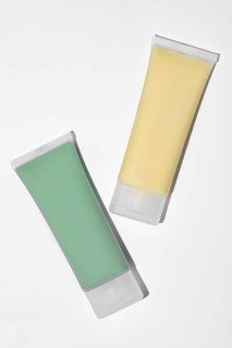 Two skincare face mask tubes, on white background. The green tube contains a spirulina, kaolin, and