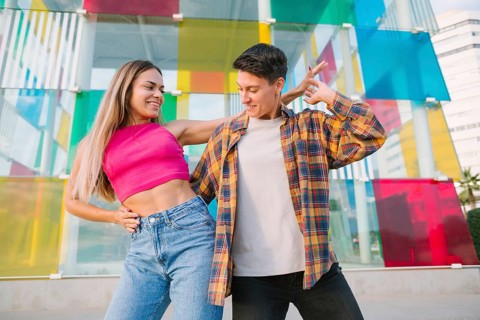 A joyful lesbian couple shares a playful dance, smiling and enjoying the moment. The vibrant glass