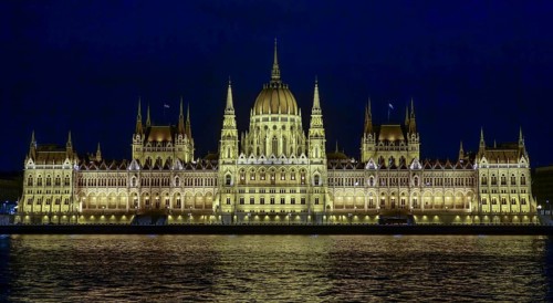 The Hungarian Parliament Building, illuminated at night, reflects its grandeur on the waters of the