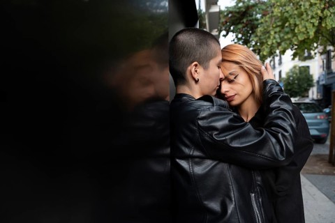 A loving lesbian couple shares an intimate, tender moment while standing closely against a wall in