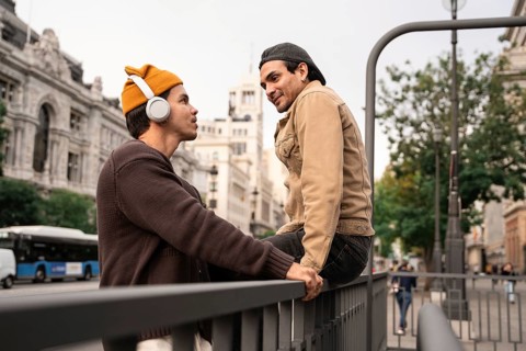 A Colombian couple enjoys a moment together in Madrid city, one listening to music with headphones,