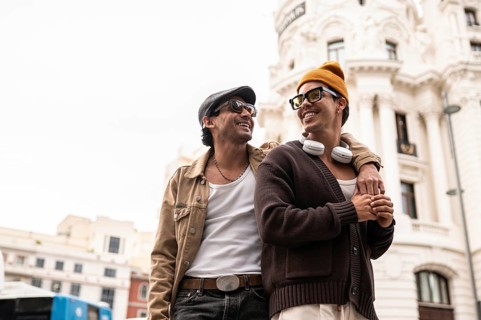 A joyful colombian gay couple enjoying a casual city walk. Both are wearing sunglasses and