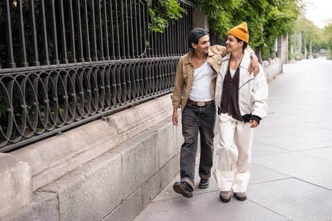 A Colombian gay couple enjoys a romantic walk, embracing each other in a casual urban setting. The