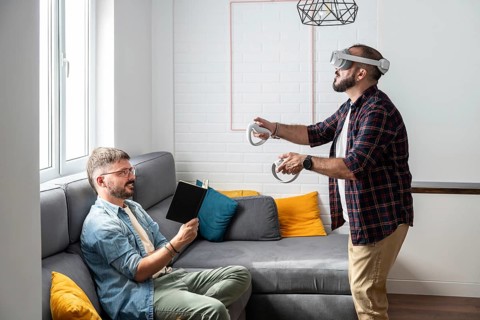 A gay couple engages in leisure activities in their living room. One reads a book while the other