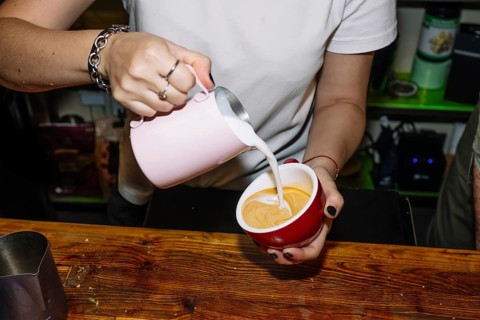 A barista skillfully pours milk into espresso to create latte art, highlighting the process of