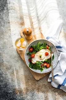 Top view of a nutritious and vibrant meal featuring fresh spinach leaves, cherry tomatoes, and a