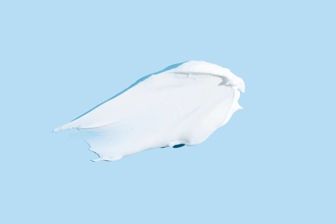 Smooth texture of a white cream or gel smear, isolated on a serene blue background, representing