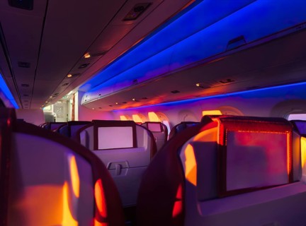 Interior view of an airplane cabin aglow with vibrant mood lighting, showcasing the comfortable
