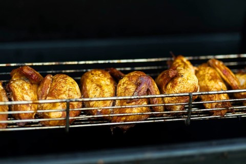 Juicy grilled chickens cooking on a metal rack, highlighting the vibrant street food scene at an