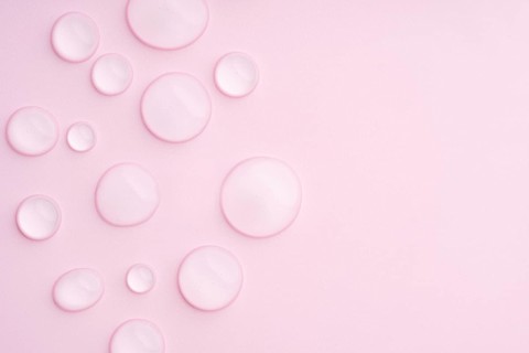 This image displays a pastel pink background with clear droplets, creating a serene and calming