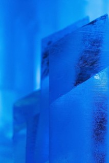 Close-up of intricately shaped ice structures illuminated with a cool blue glow at a temporary ice