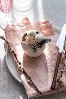 From above, an artistic Easter table arrangement features a porcelain bowl with speckled eggs,