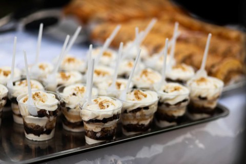A tray of delicious layered dessert cups, each topped with whipped cream and crunch, beautifully