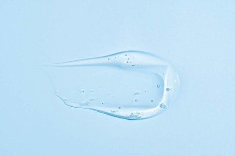 A translucent blue gel-like substance with a smooth, creamy texture, smeared in an elegant, fluid