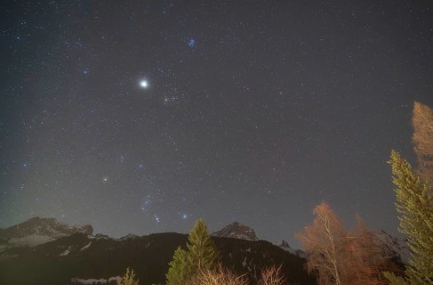 The constellations of Orion and Taurus shine brightly in the night sky, accompanied by Jupiter,
