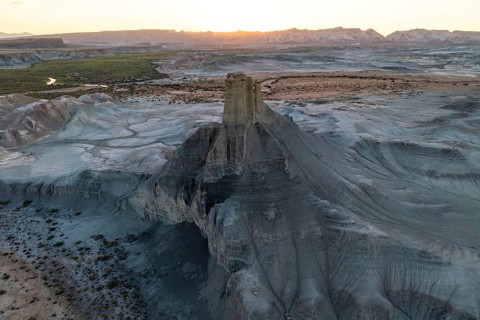 A sweeping aerial view captures the vast, eroded terrain of Utah's desert at sunset, highlighting